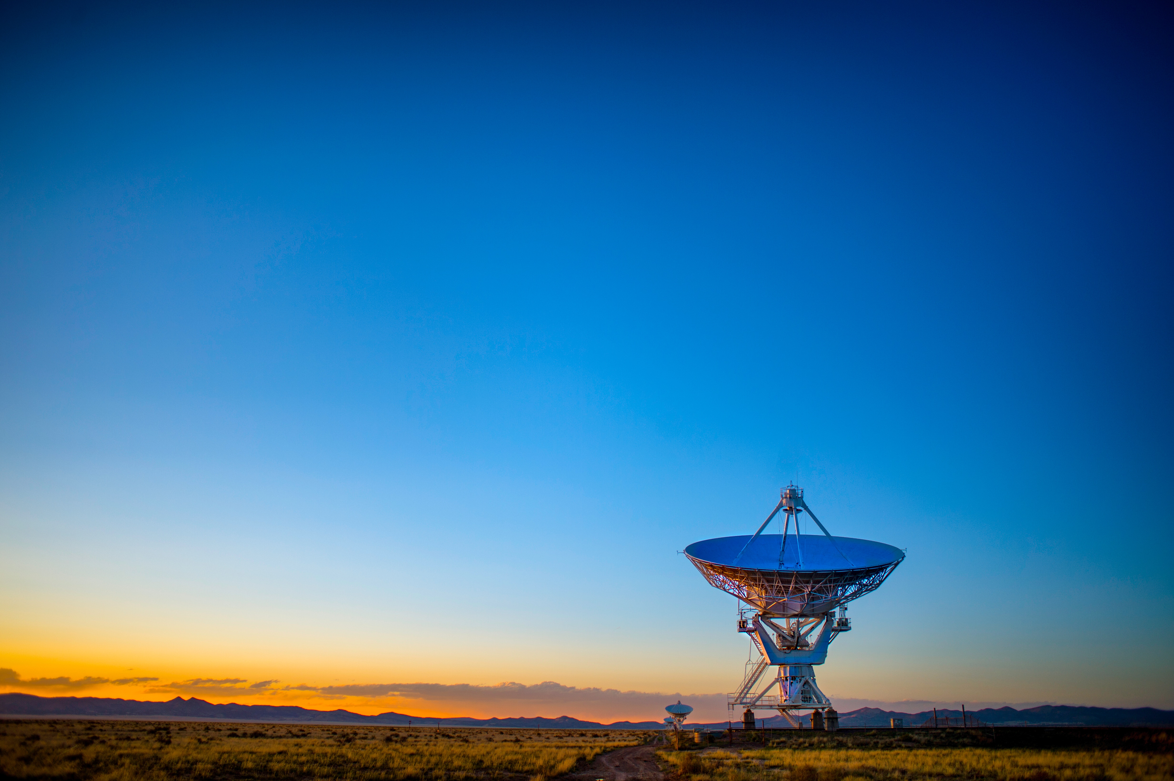 A photo of a radar dish pointed upward at sunrise